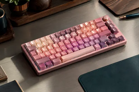 Clavier mécanique compact rose dégradé avec touches PBT, bouton multifonction et éclairage RVB sur un bureau sobre.